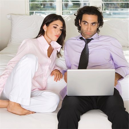 Close-up of a businessman and a businesswoman sitting on the bed using a laptop Stock Photo - Premium Royalty-Free, Code: 625-00901465