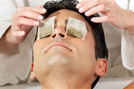 Mid section view of a massage therapist putting teabags on a young man's eyes Stock Photo - Premium Royalty-Free, Code: 625-00901572