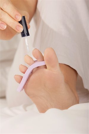 Low section view of a mid adult woman applying nail polish on her toenails Stock Photo - Premium Royalty-Free, Code: 625-00901674