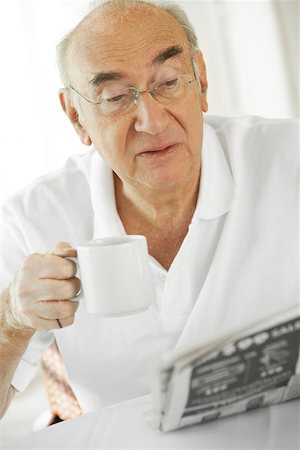 simsearch:625-02931670,k - Gros plan d'un homme senior tenant une tasse de café, lire un journal Photographie de stock - Premium Libres de Droits, Code: 625-00901776