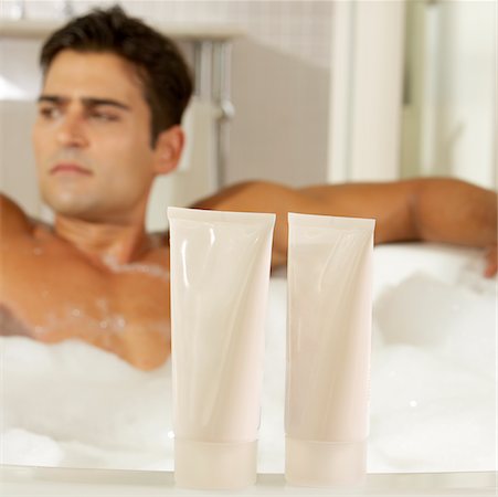 simsearch:625-00902133,k - Close-up of two bottles of moisturizer with a young man in a bathtub behind it Foto de stock - Royalty Free Premium, Número: 625-00901872