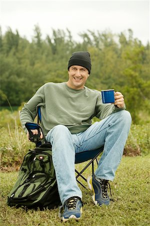 Ein älterer Mann sitzt auf einem Klappstuhl hält einen Becher Porträt Stockbilder - Premium RF Lizenzfrei, Bildnummer: 625-00901924
