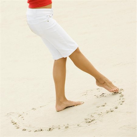 Low section view of a girl drawing in sand with her toe Stock Photo - Premium Royalty-Free, Code: 625-00901978