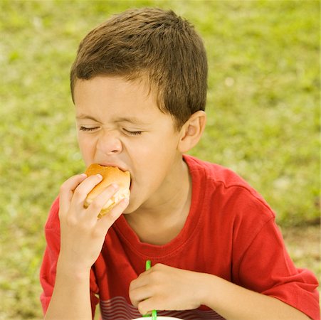 Close-up of a boy eating a burger Stock Photo - Premium Royalty-Free, Code: 625-00901991