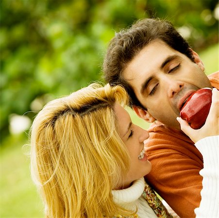 Close-up of a young woman feeding an apple to a mid adult man Stock Photo - Premium Royalty-Free, Code: 625-00902096