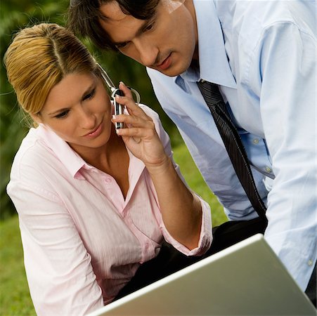 Close-up of a businessman and a businesswoman working on a laptop and talking on a mobile phone Stock Photo - Premium Royalty-Free, Code: 625-00902479
