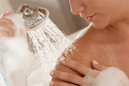 Close-up of a young woman holding a shower head Stock Photo - Premium Royalty-Free, Code: 625-00903048