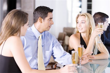 Two young women and a mid adult man sitting at a bar counter Stock Photo - Premium Royalty-Free, Code: 625-00903082