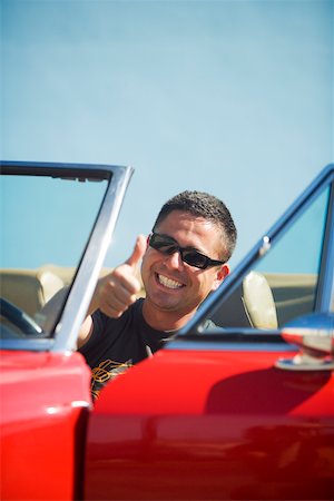 Close-up of a young man sitting in a car showing a thumbs up sign Stock Photo - Premium Royalty-Free, Code: 625-00903142
