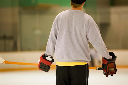 Rear view of an ice hockey player holding an ice hockey stick Stock Photo - Premium Royalty-Free, Code: 625-01038187