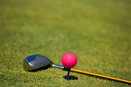 Close-up of a golf ball on a tee with a golf club on the grass Stock Photo - Premium Royalty-Free, Code: 625-01038226