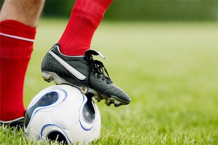 Close-up of a person's foot resting on a soccer ball Stock Photo - Premium Royalty-Free, Code: 625-01038300