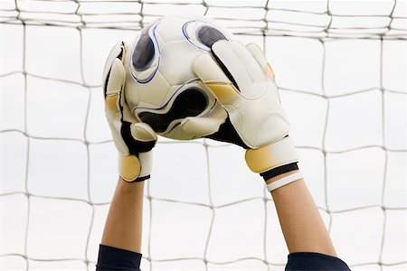 Close-up of a goalie's hands holding a soccer ball Stock Photo - Premium Royalty-Free, Code: 625-01038403