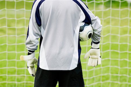 Rear view of a goalie with a soccer ball under his arm Stock Photo - Premium Royalty-Free, Code: 625-01038425