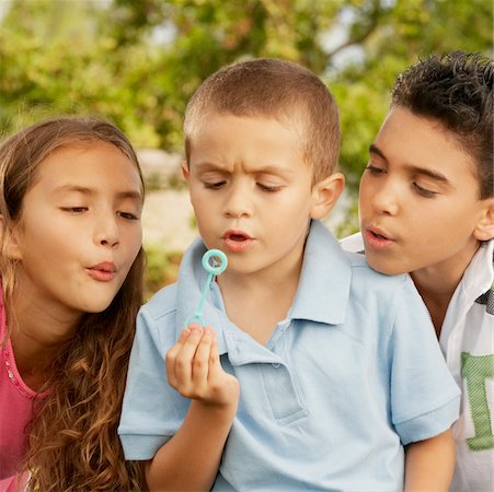 Close-up of a boy blowing bubbles with his brother and sister Stock Photo - Premium Royalty-Free, Code: 625-01038703