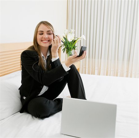 flowers and night table - Businesswoman applying eyeshadow on her eyes with a laptop in front of her Stock Photo - Premium Royalty-Free, Code: 625-01038947