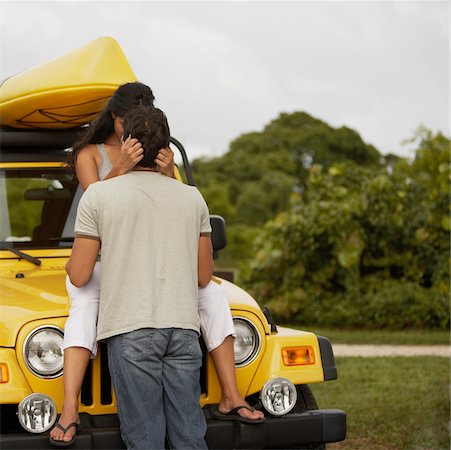 simsearch:625-01095436,k - Young woman sitting on the bonnet of a jeep and kissing a mid adult man Stock Photo - Premium Royalty-Free, Code: 625-01039134