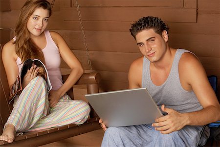 Portrait of a young man holding a laptop with a young woman sitting on a porch swing Stock Photo - Premium Royalty-Free, Code: 625-01039149
