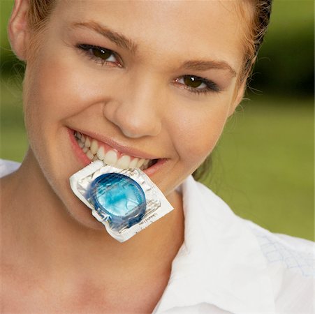 Portrait of a teenage girl holding a condom in her mouth Stock Photo - Premium Royalty-Free, Code: 625-01039143