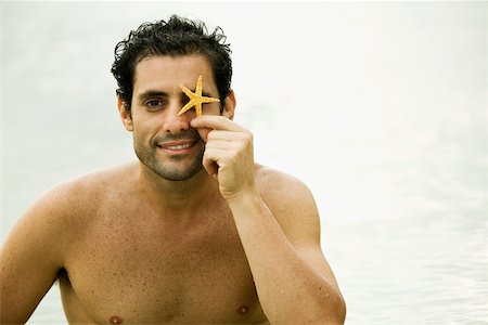 sea starfish pictures - Portrait d'un homme adult moyen tenant une étoile de mer devant ses yeux Photographie de stock - Premium Libres de Droits, Code: 625-01039535