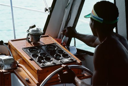 A boat captain navigates a powerboat off the shore of Jamaica Fotografie stock - Premium Royalty-Free, Codice: 625-01040839