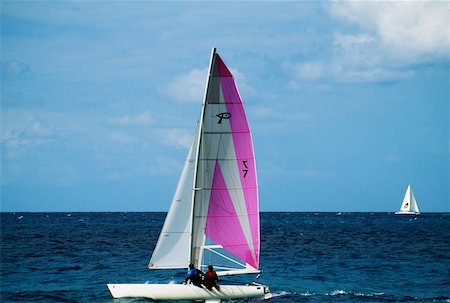 st martin - A sailboat participates in the Heiniken Regatta on the Dutch side of the island of St. Maarten in the Caribbean. Foto de stock - Sin royalties Premium, Código: 625-01040901