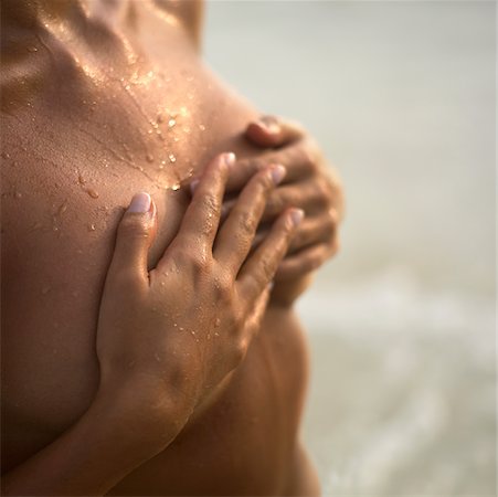 Mid section view of a young woman covering her breast with her hands Stock Photo - Premium Royalty-Free, Code: 625-01095359