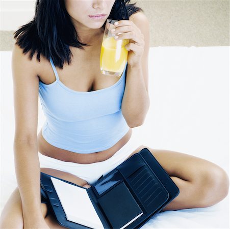 simsearch:640-01362778,k - Close-up of a young woman sitting on the bed and holding a glass of orange juice Foto de stock - Sin royalties Premium, Código: 625-01095374