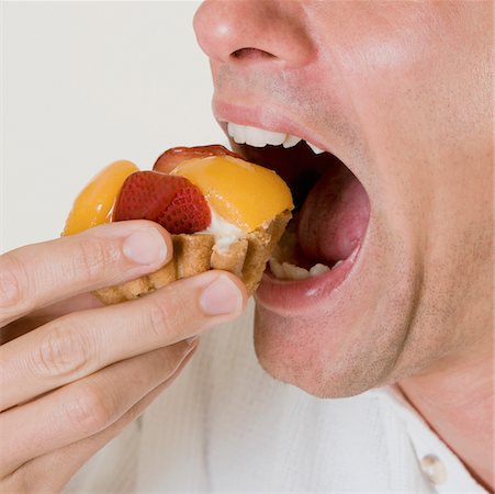 peach slice - Close-up of a young man eating a fruit tart Stock Photo - Premium Royalty-Free, Code: 625-01095375