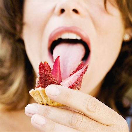 Close-up of a young woman licking a strawberry tart Fotografie stock - Premium Royalty-Free, Codice: 625-01095383