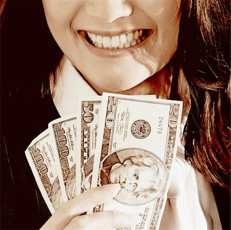 Close-up of a businesswoman holding dollar bills and smiling Stock Photo - Premium Royalty-Free, Code: 625-01095402