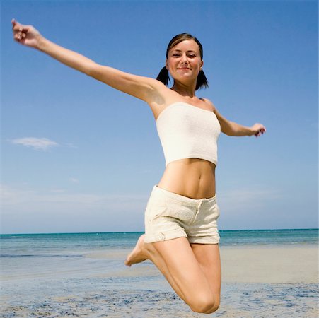 Close-up of a young woman jumping on the beach Stock Photo - Premium Royalty-Free, Code: 625-01095437