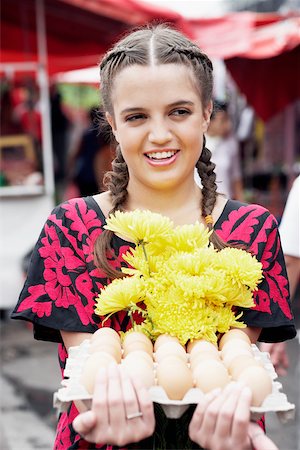 Close-up of a young woman holding a bunch of flowers and an egg carton Stock Photo - Premium Royalty-Free, Code: 625-01095889