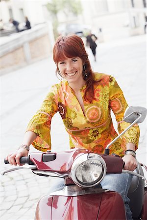 simsearch:625-01265118,k - Portrait of a young woman sitting on a motor scooter and smiling Fotografie stock - Premium Royalty-Free, Codice: 625-01096236