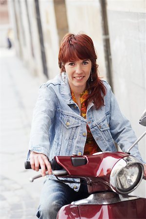 simsearch:625-01265118,k - Portrait of a young woman sitting on a motor scooter and smiling Fotografie stock - Premium Royalty-Free, Codice: 625-01096243