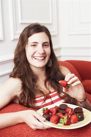 Portrait d'une jeune femme tenant une assiette de fraises au chocolat et souriant Photographie de stock - Premium Libres de Droits, Code: 625-01096895