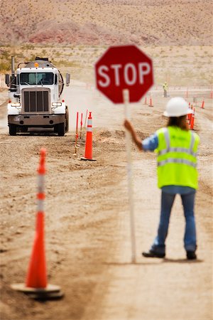 road signs safety - Rear view of a man holding a stop sign on a dirt road Stock Photo - Premium Royalty-Free, Code: 625-01097230