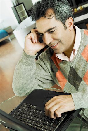 simsearch:625-01097695,k - Close-up of a mature man talking on a mobile phone and using a laptop Foto de stock - Royalty Free Premium, Número: 625-01097482