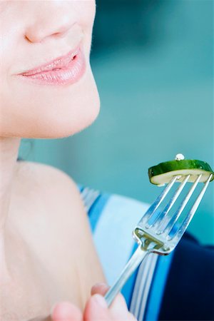 Close-up of a young woman holding a slice of cucumber with a fork Stock Photo - Premium Royalty-Free, Code: 625-01097529