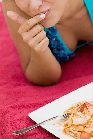 people eating seafood - Close-up of a young woman with her finger on her lips and a plate of pasta in front of her Stock Photo - Premium Royalty-Free, Code: 625-01097521