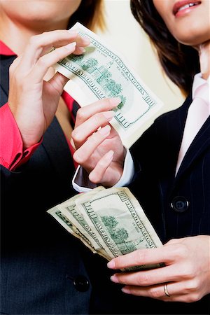 Mid section view of a businesswoman giving one hundred dollar bill to another businesswoman Stock Photo - Premium Royalty-Free, Code: 625-01097539