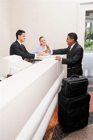 simsearch:625-02931286,k - Businessman and two receptionists at a hotel reception Stock Photo - Premium Royalty-Free, Code: 625-01097570