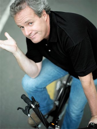 Portrait d'un homme d'âge mûr assis sur un vélo et faire des gestes Photographie de stock - Premium Libres de Droits, Code: 625-01097635