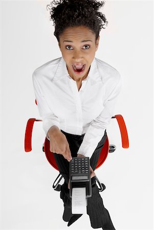 High angle view of a businesswoman operating an adding machine tape with her mouth open Stock Photo - Premium Royalty-Free, Code: 625-01097793