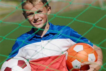 simsearch:640-02764424,k - Portrait of a soccer player standing behind the net and holding two soccer balls Stock Photo - Premium Royalty-Free, Code: 625-01091878