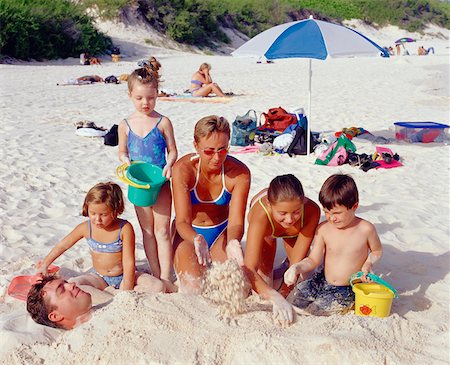 simsearch:6126-08635074,k - Mid adult woman covering a mid adult man in sand with her three daughters and a son, Bermuda Stock Photo - Premium Royalty-Free, Code: 625-01092047