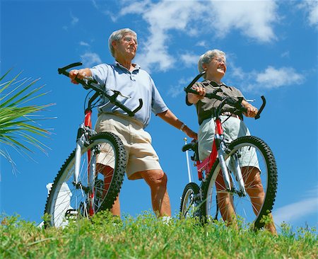 Low angle view of a senior couple standing with their bicycles, Bermuda Stock Photo - Premium Royalty-Free, Code: 625-01092061