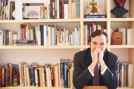 simsearch:625-01096766,k - Portrait of a businessman sitting in front of book shelves Stock Photo - Premium Royalty-Free, Code: 625-01092791