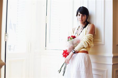 Portrait d'une jeune femme contre un mur et tenant un bouquet de fleurs Photographie de stock - Premium Libres de Droits, Code: 625-01092930