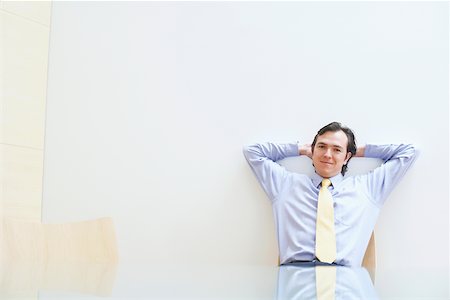 Portrait of a businessman relaxing with his hands behind his head in an office Stock Photo - Premium Royalty-Free, Code: 625-01093131